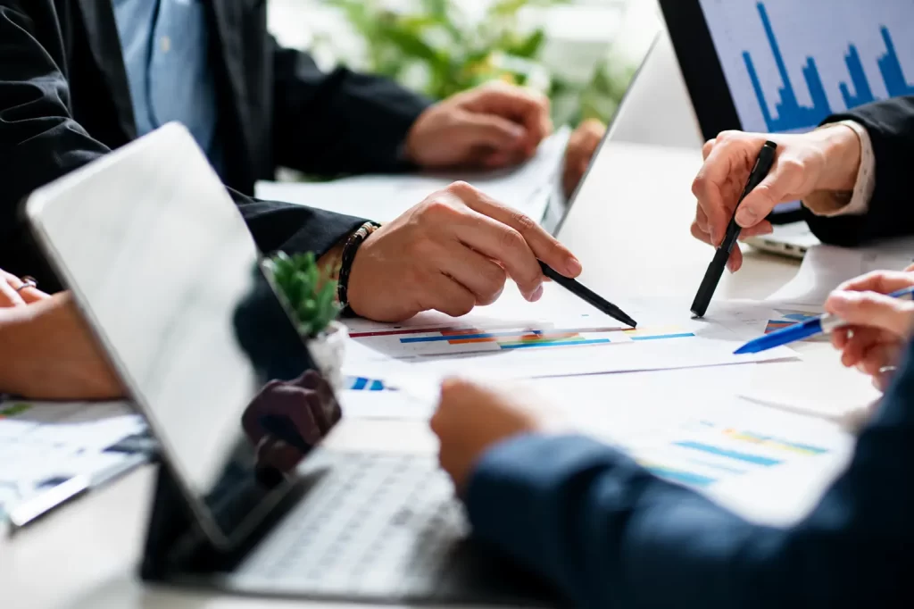 Business team reviewing SEM advertising performance, campaign data, keyword strategy, and digital marketing reports during a planning meeting.